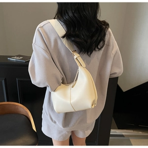 Detail of cream white leather crescent shoulder bag with golden buckle and stitching