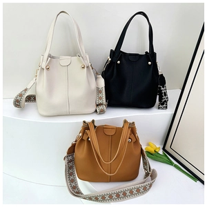 Three bucket bags with ethnic woven straps in cream, black, and caramel brown finishes
