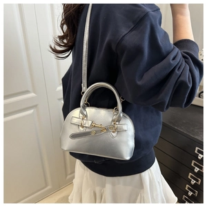Detail of silver shell bag showing metallic texture, buckle strap, and gold hardware