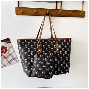 Detail of printed tote bag set with palm tree pattern and brown leather handles