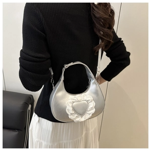 Détail du sac croissant argenté avec cœur en dentelle et finition métallique