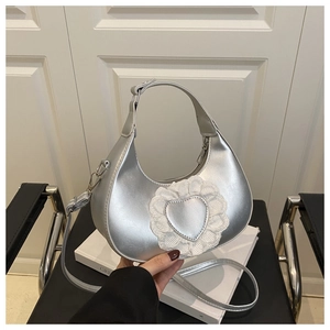 Détail du sac hobo argenté avec un patch cœur en dentelle et fermeture éclair