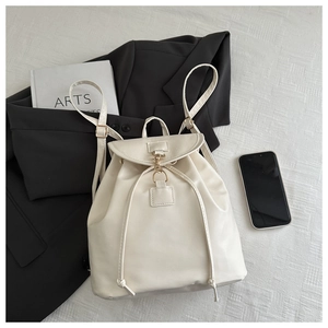 Flat lay of cream faux leather backpack with drawstring closure and metal buckle detail