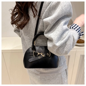 Detail of black shell bag with decorative belt strap and gold buckle on casual outfit