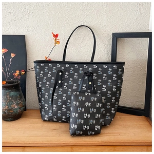 Detail of printed large capacity tote bag set with matching small clutch and palm tree design