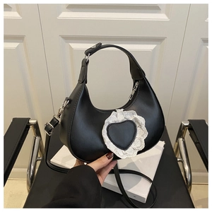 Détail du sac hobo noir avec breloque cœur en dentelle blanche et bandoulière ajustable