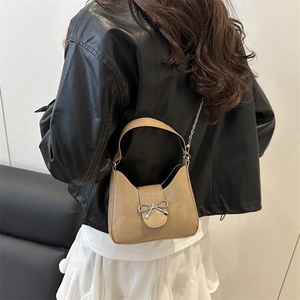 Khaki shoulder bag with silver bow accent and metal chain strap shown on model