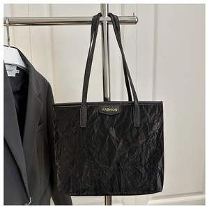 Detail of black wrinkled texture tote bag with Fashion tag hanging on a hanger