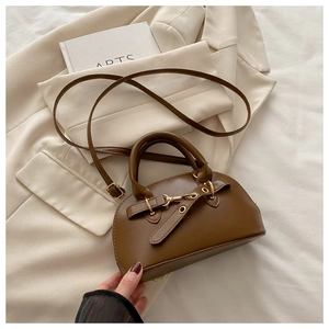 Detail shot of the brown leather shell bag featuring vintage gold buckles and fine texture