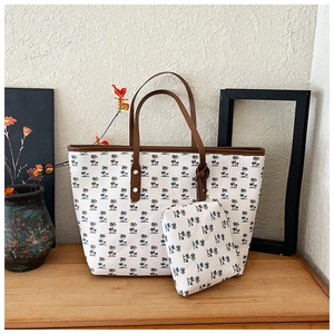 Canvas tote bag with palm tree print featuring leather handles and matching inner pouch