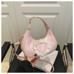 Détail d'un sac hobo rose avec applique de cœur en dentelle et bandoulière réglable