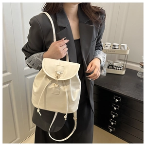 Detail shot of the cream white faux leather backpack with gold metal clasp and drawstring