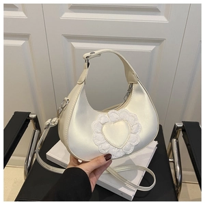 Détail du sac demi-lune blanc perle avec patch coeur en dentelle et boucles argent