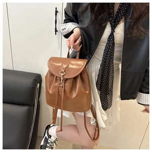 Detail of brown leather backpack featuring vintage gold buckles and drawstring closure