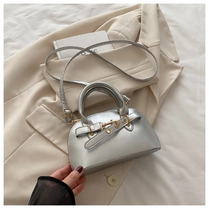 Top view of silver shell bag with metallic finish and belt buckle on beige fabric