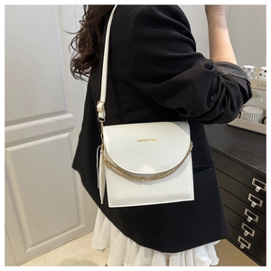 Vue détaillée d'un sac bandoulière blanc avec chaînes dorées et lettrage de mode