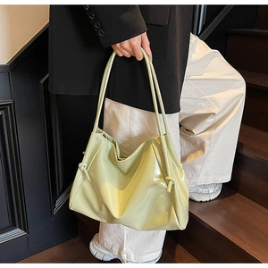Détail du sac cabas en cuir verni vert pistache avec bretelles nouées et design plissé