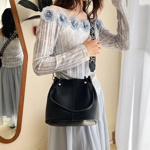 Black pebbled leather bucket bag with gold rivets and patterned wide fabric strap