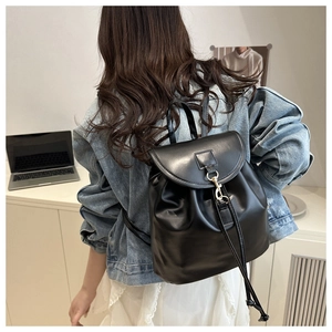 Detail of minimalist black leather backpack with flap metal hook and drawstring closure