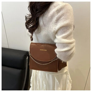 Détail d'un sac bandoulière en cuir marron avec chaîne dorée et logo Fashion & Bags