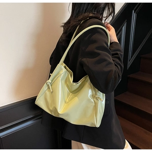 Detail of light green glossy leather tote bag showing smooth texture and knot strap detail
