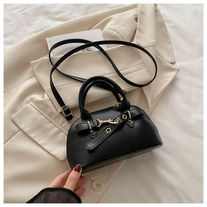 Close-up of black shell handbag with gold buckle detail and adjustable strap on a blazer
