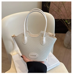 Détail du sac seau blanc tressé avec ouverture ondulée en W et étiquette en cuir mode