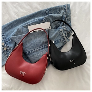 Flat lay of black and burgundy half-moon baguette bags with silver bow accents