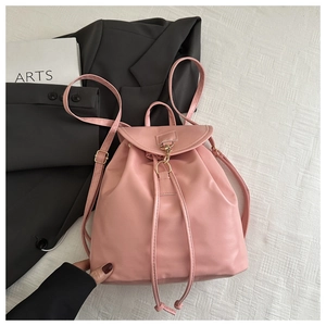 Detail showing pink mini backpack with drawstring and golden buckle held by a hand