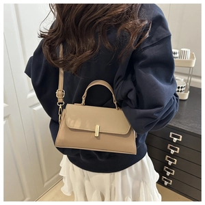 Rear view of a khaki crossbody bag shown with a golden lock on a female model