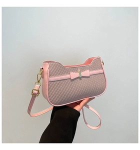 Detail of pink bow handbag showing woven texture stitching and golden hardware buckle