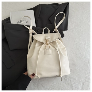 Detail view of cream white leather backpack with metal hook and drawstring on soft fabric