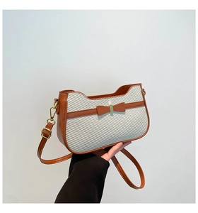 Detail of woven fabric texture and brown leather bow on an elegant crossbody handbag