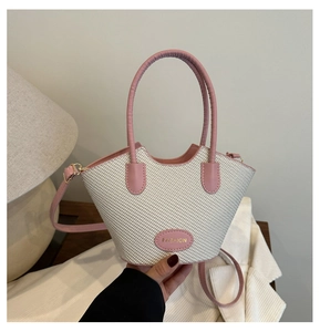 Gros plan sur un sac seau tissé rose avec poignée en cuir et détail étiquette mode