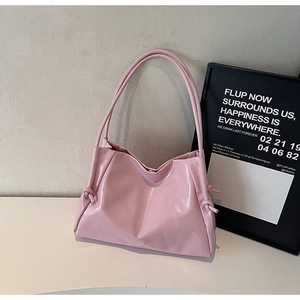Detail of light pink glossy tote bag with stylish knot strap and shiny patent finish