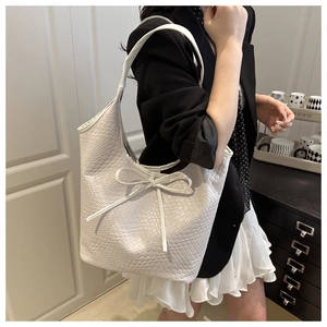 Close-up of white woven texture and delicate bow detail on the hobo underarm tote bag
