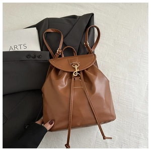 Detail of caramel brown faux leather backpack with gold lobster clasp and drawstring closure