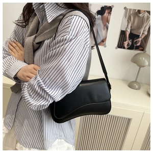Classic black leather underarm bag with magnetic flap closure styled on a model