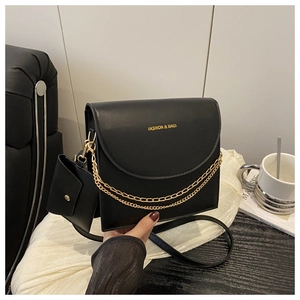 Close-up of black leather crossbody bag with gold fashion lettering and chain detail