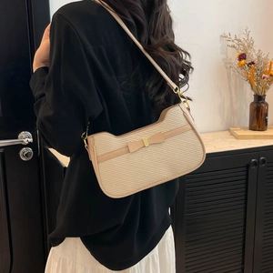Sac à bandoulière tissé beige avec nœud et garniture en cuir marron sur un mannequin femme
