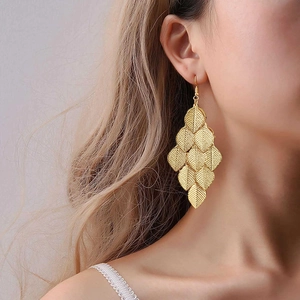 Detailed view of layered gold leaf tassel earrings worn by a model in bohemian style