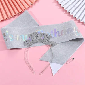 Detail of silver glitter birthday sash and tiara headband set on pink party background
