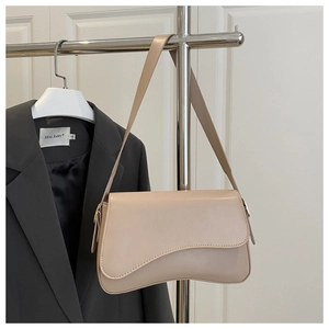 Close-up of minimalist beige faux leather shoulder bag with asymmetrical flap design