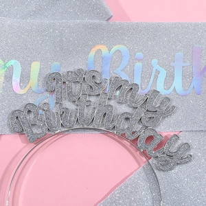 Close-up of silver glitter Birthday Girl headband and sash set on pink background