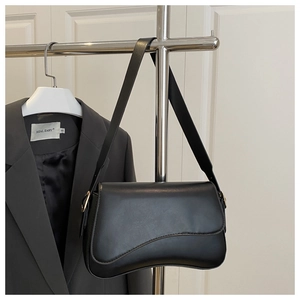 Close-up of black smooth leather underarm saddle bag with gold-tone metal hardware