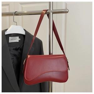Detail of deep red matte leather shoulder bag with unique curved base on a metal stand