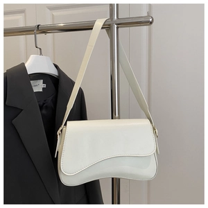 Detail of cream white faux leather shoulder bag with gold buckle on a minimalist strap