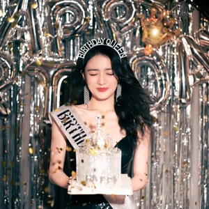 Close-up of Birthday Queen rhinestone tiara and silver sash on a party model