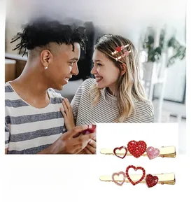 Dettaglio di fermagli per capelli a cuore in cristallo rosso e rosa con base dorata