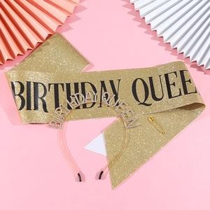 Détail de l'écharpe Birthday Queen pailletée et du diadème strass sur fond rose de fête